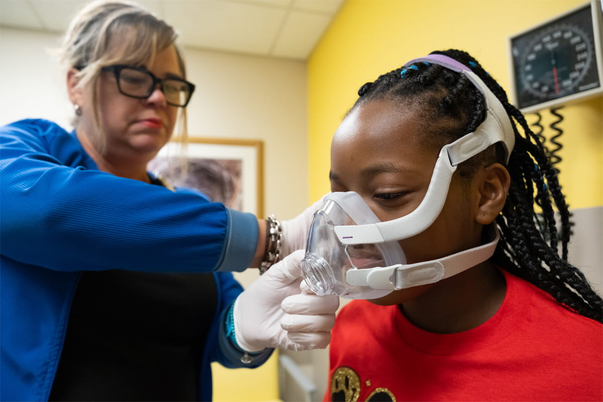 Patient in clinic wearing CPAP machine with the help of a nurse.